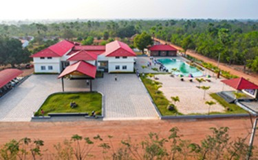 Experience the luxurious front view of the club house and beach-themed swimming pool at USM Infra Go Ranch Resort Sandalwood Farm Plots